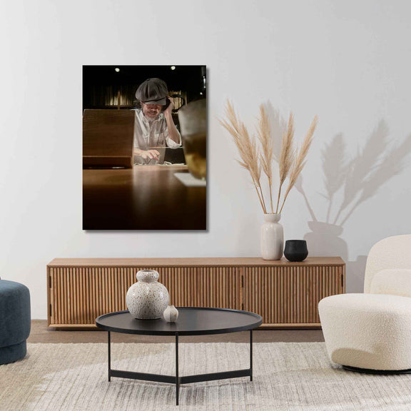 Modern living room with a TV displaying a person working, a wooden cabinet, and decorative items.