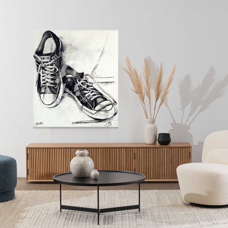 Living room with a painting of black sneakers on the wall, a wooden cabinet, and modern furniture.