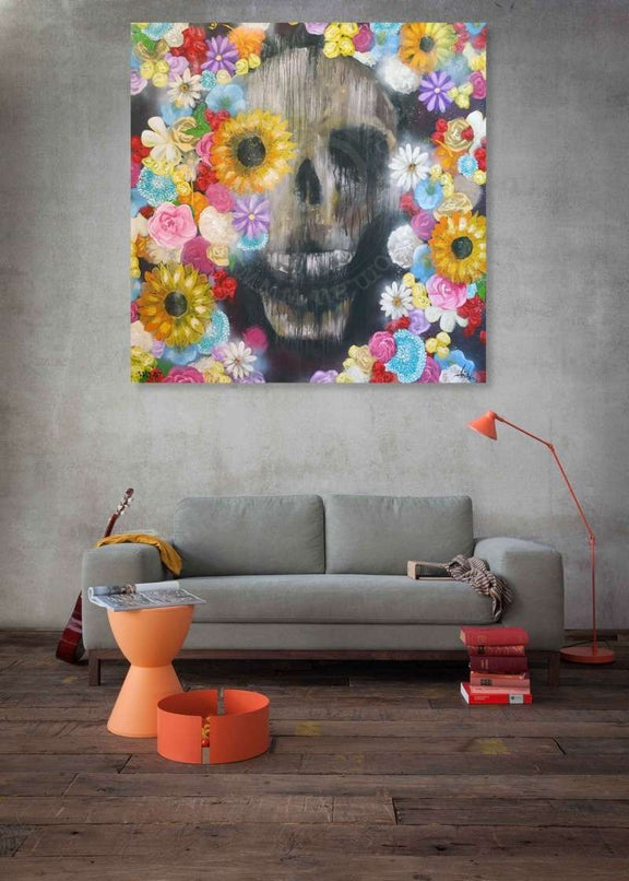 Living room with a gray sofa, orange stool, and colorful floral skull painting on the wall.