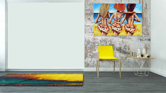 Room interior with a colorful painting of three women in bikinis, a yellow chair, and a small table.
