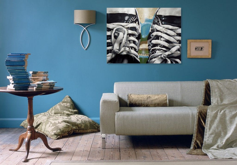 Living room with a gray sofa, wooden side table, and wall art of shoes.