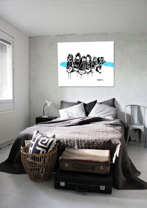 Modern bedroom with a bed, baskets, and suitcases against a wall with a graphic art print.