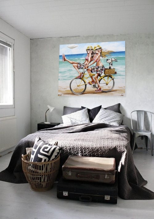 Bedroom with a large wall art of two people on a bicycle by the beach.