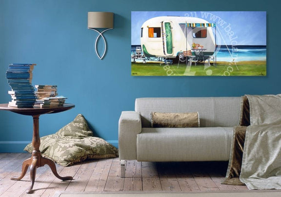 Living room with a gray sofa, wooden side table, and wall art of a camper.