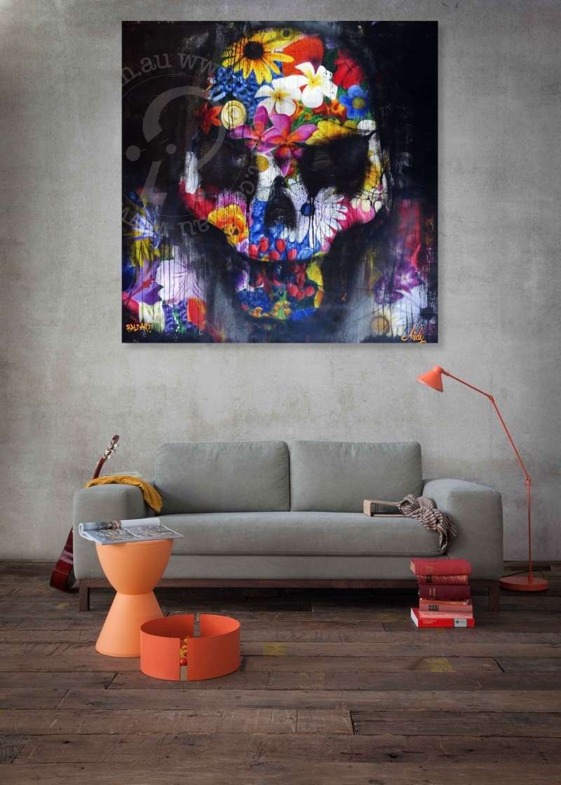 Colorful skull painting on a wall above a gray sofa in a living room.