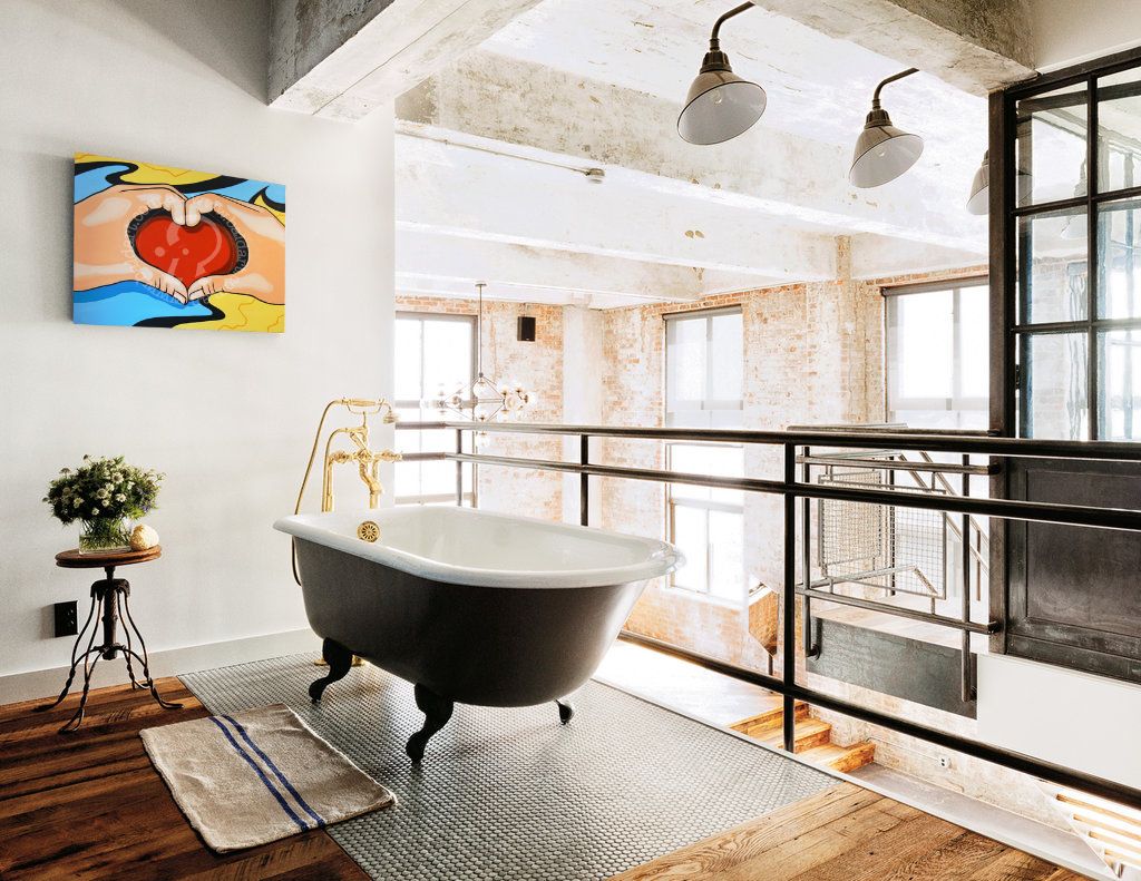 Modern bathroom with freestanding bathtub, large windows, and colorful artwork on wall.