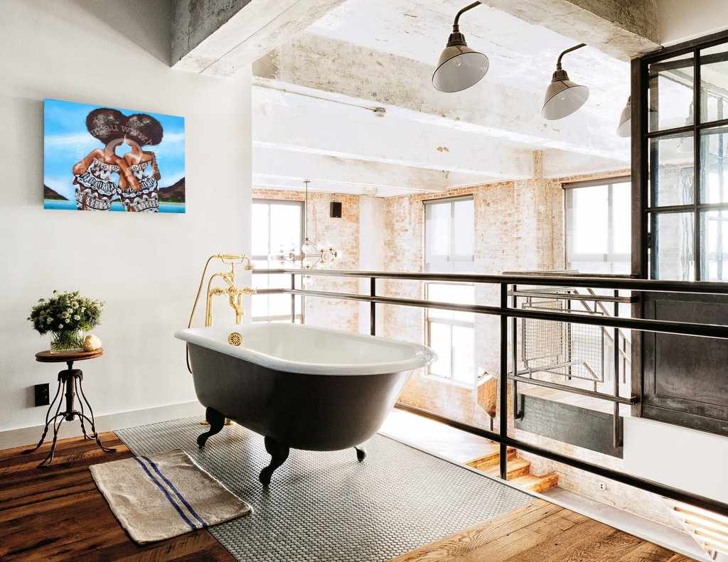 Modern bathroom with freestanding bathtub, large windows, and decorative elements.