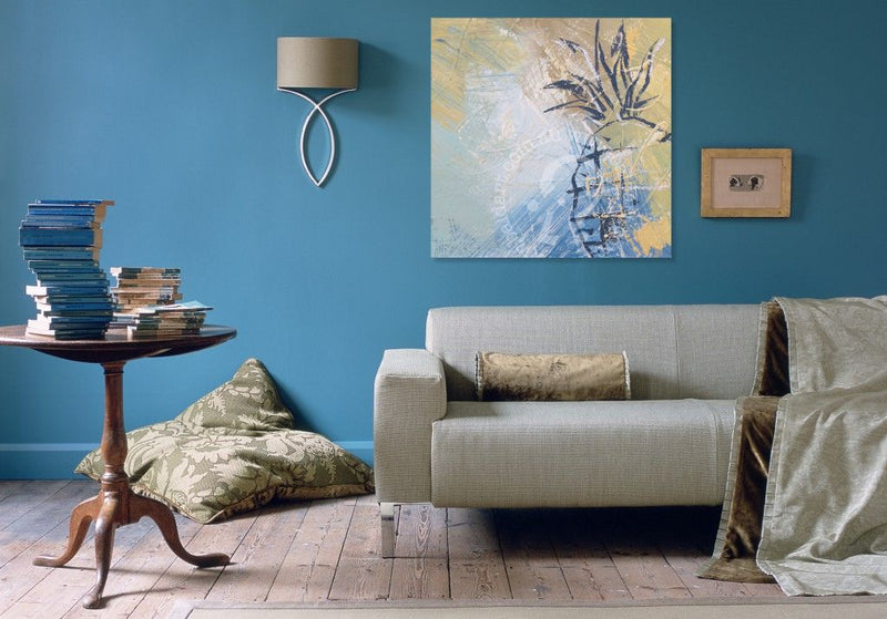 Living room with a gray sofa, wooden side table, and abstract painting on a blue wall.