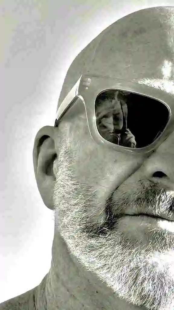 Close-up of a person wearing reflective sunglasses with a neutral background