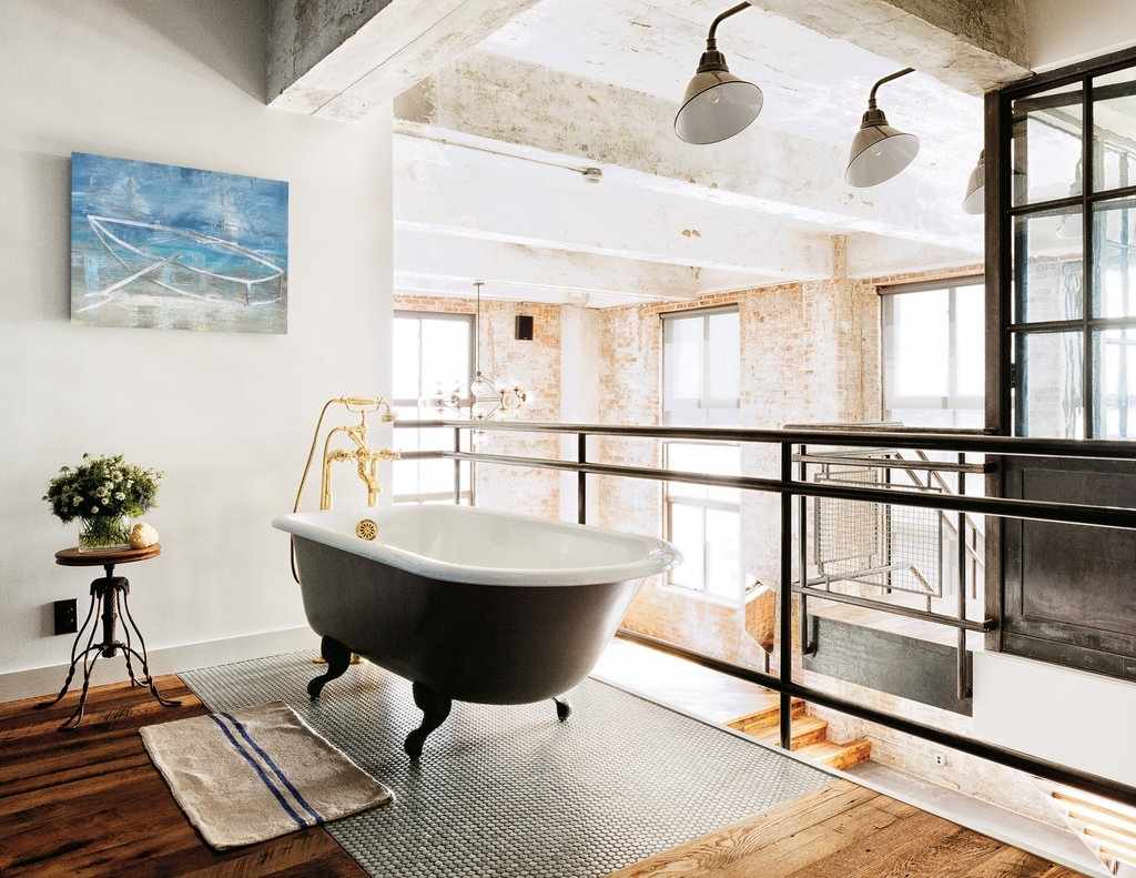 Modern bathroom with freestanding bathtub, large windows, and industrial decor.