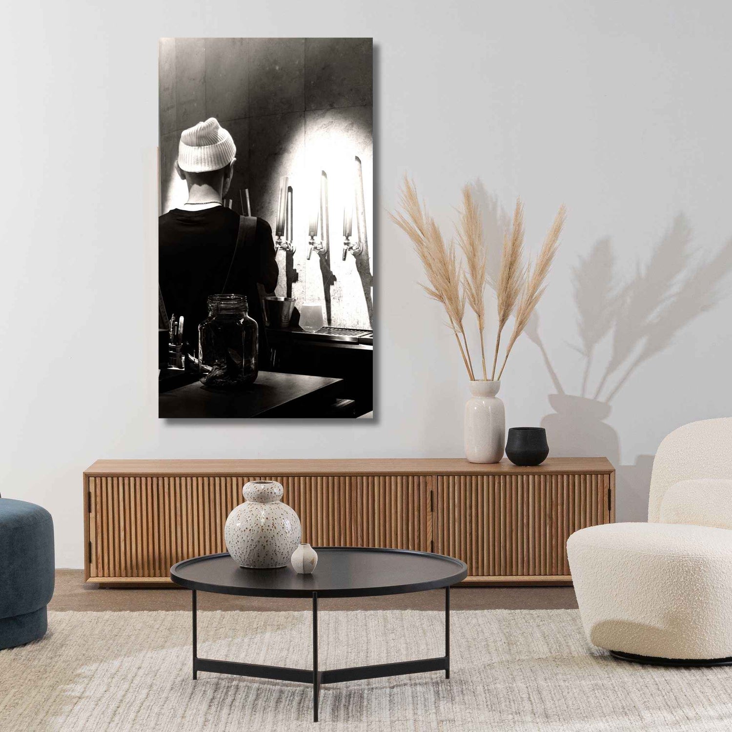 Modern living room with a large black and white painting, wooden cabinet, and decorative items.