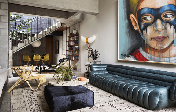 A stylish living room showcasing a vibrant painting on the wall, complemented by inviting seating and warm lighting.