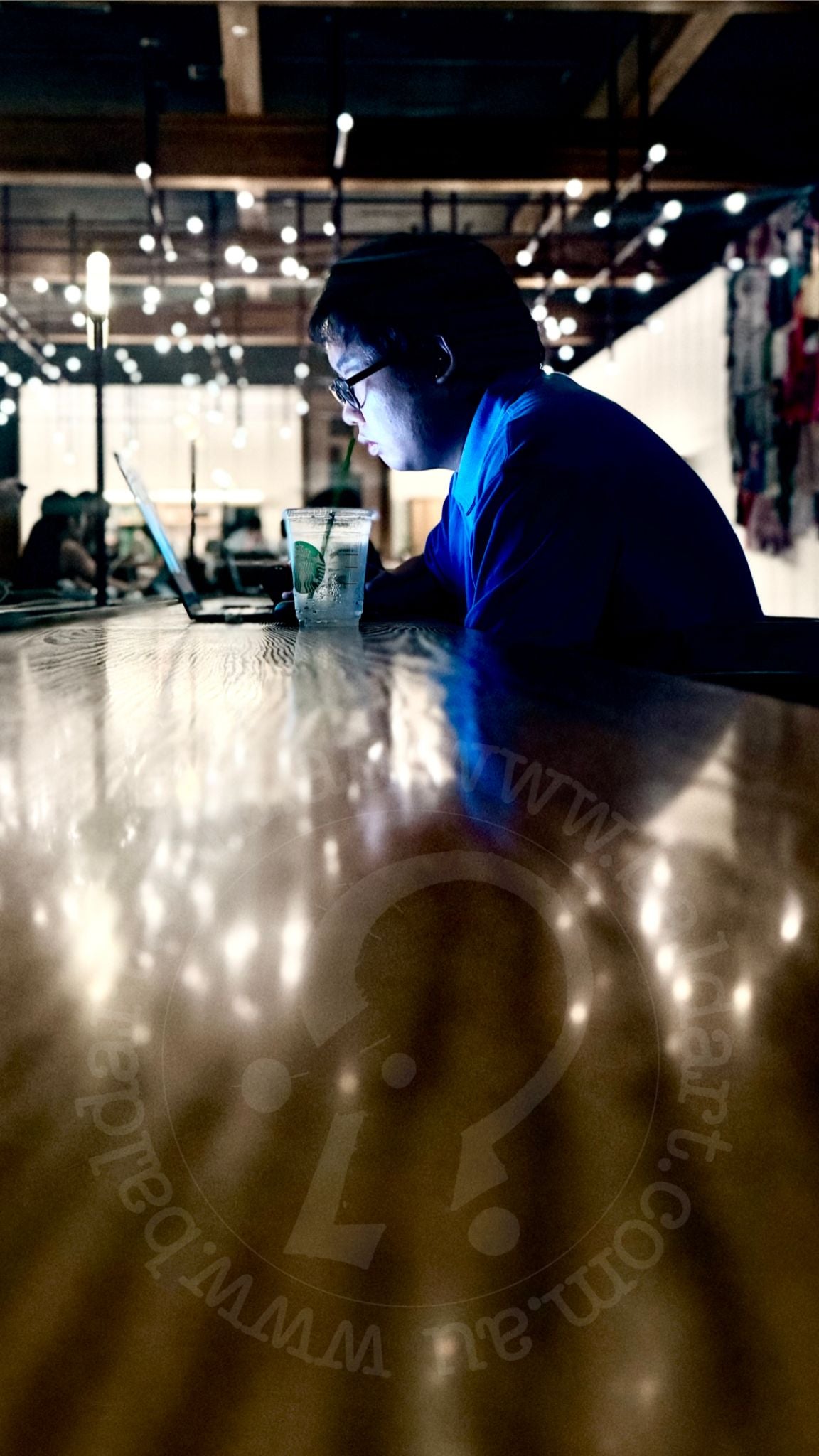 Person sitting at a table in a dimly lit room with string lights