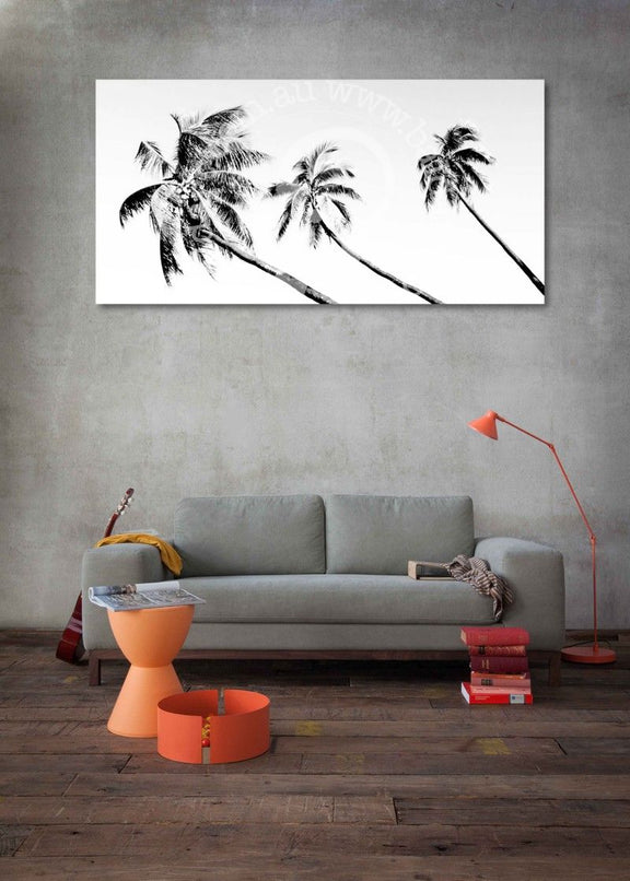 Living room with gray sofa, orange stool, and lamp, featuring a large wall art of black palm trees.