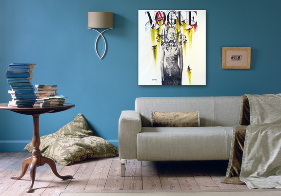 Living room with a gray sofa, wooden side table, and 'Vogue' magazine cover on the wall.