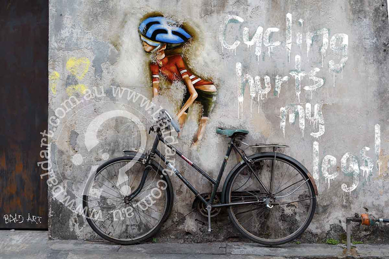 A bicycle leans against a wall featuring a painting of a person, creating a vibrant urban scene.