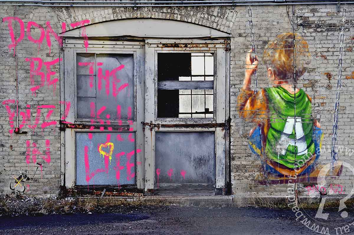 A piece of contemporary art featuring a stylized character with a spray paint can, predominantly in pink and gray tones, on a wall with visible graffiti.