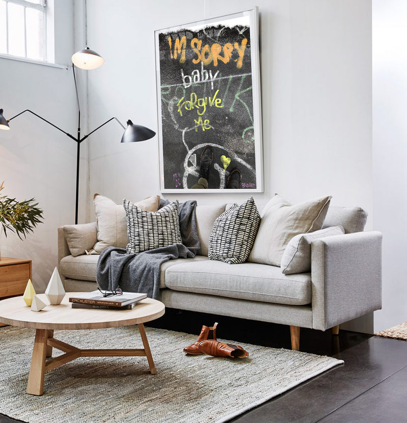 A cozy living room featuring a couch, coffee table, and a colorful painting on the wall.