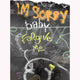 A photograph featuring a piece of contemporary urban street art with the text 'I'm sorry baby' in a stylized font, on a graffiti-covered wall.