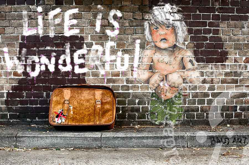 A piece of contemporary art featuring the text 'Life is Wonderful' and an illustration of a person with a suitcase, painted on a wall.