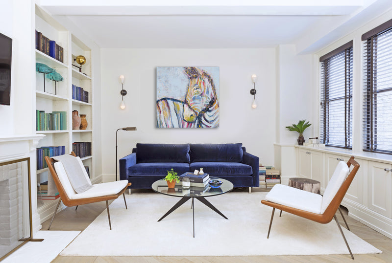 A stylish living room showcasing a vibrant painting on the wall, complemented by inviting seating and warm lighting.
